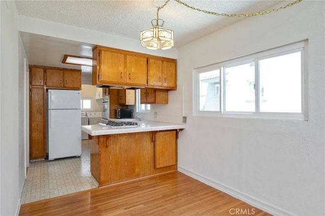827 S Leland St, San Pedro, CA 90731 - kitchen with white appliances, brown cabinetry, a peninsula, light countertops, and baseboards
