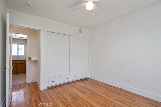 827 S Leland St, San Pedro, CA 90731 - unfurnished bedroom featuring light wood-style floors, a textured ceiling, baseboards, a closet, and a sink