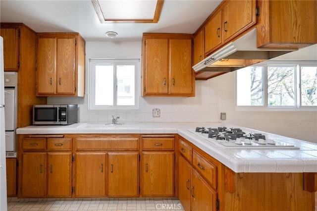 827 S Leland St, San Pedro, CA 90731 - kitchen with stainless steel microwave, white gas cooktop, brown cabinetry, and a sink