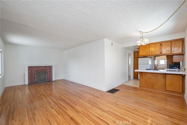 827 S Leland St, San Pedro, CA 90731 - unfurnished living room with light wood-style flooring, a fireplace, baseboards, a chandelier, and a textured ceiling