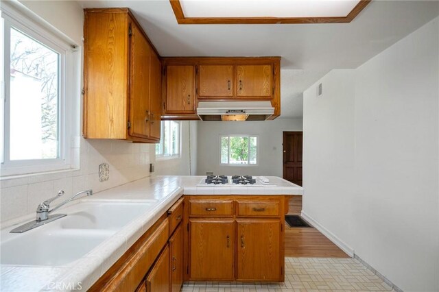 827 S Leland St, San Pedro, CA 90731 - kitchen with a sink, under cabinet range hood, a peninsula, white gas stovetop, and brown cabinetry