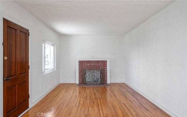827 S Leland St, San Pedro, CA 90731 - unfurnished living room with light wood-type flooring, a fireplace, baseboards, and a textured ceiling