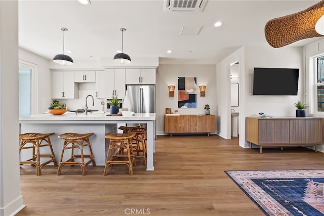 19041 Main St Unit 109, Huntington Beach, CA 92648 - kitchen with freestanding refrigerator, a kitchen breakfast bar, white cabinetry, light countertops, and recessed lighting