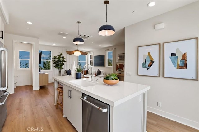 19041 Main St Unit 109, Huntington Beach, CA 92648 - kitchen featuring appliances with stainless steel finishes, a sink, white cabinets, light wood-style flooring, and light countertops