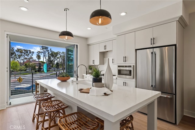 19041 Main St Unit 109, Huntington Beach, CA 92648 - kitchen featuring appliances with stainless steel finishes, a breakfast bar, light wood-style flooring, light countertops, and white cabinetry