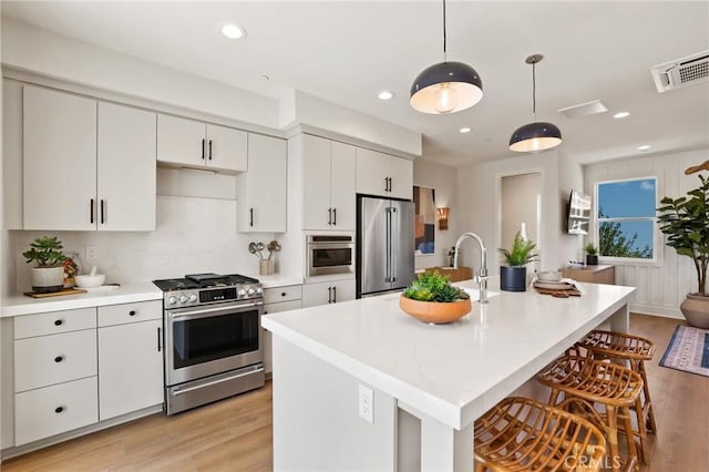 19041 Main St Unit 109, Huntington Beach, CA 92648 - kitchen featuring stainless steel appliances, light wood-style flooring, light countertops, a kitchen bar, and a kitchen island with sink