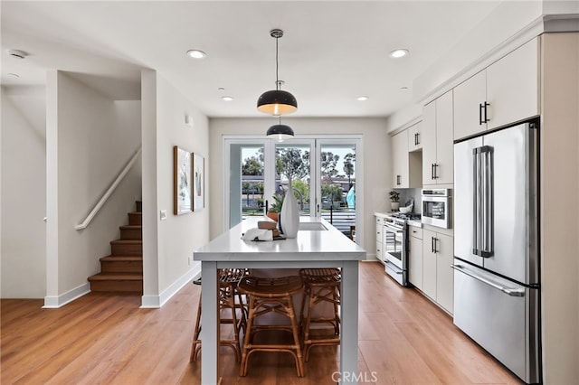 19041 Main St Unit 109, Huntington Beach, CA 92648 - kitchen with premium appliances, light countertops, white cabinets, light wood-type flooring, and recessed lighting