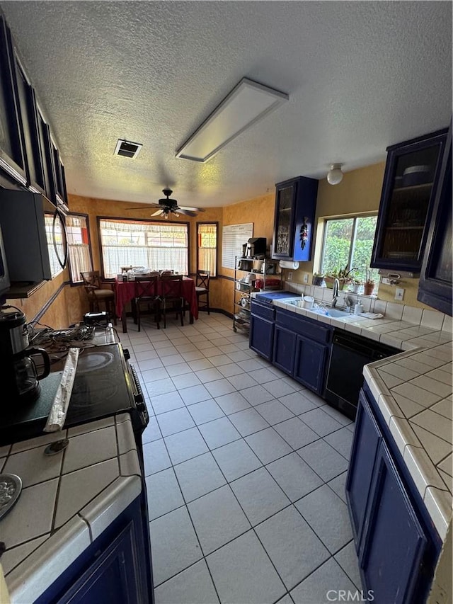 4521 Southern Breeze Dr, Bakersfield, CA 93313 - kitchen featuring tile countertops, a textured ceiling, light tile patterned flooring, black appliances, and a sink