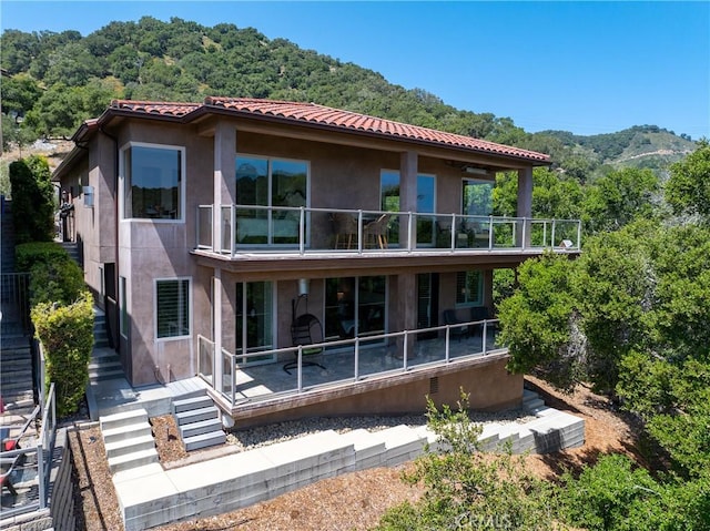 2815 Rock Wren Ln, Avila Beach, CA 93424 - rear view of property with stucco siding, stairs, a balcony, and a view of trees