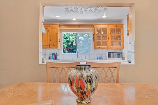22532 Dolorosa St, Woodland Hills, CA 91367 - kitchen with tile counters, stainless steel microwave, backsplash, and glass insert cabinets