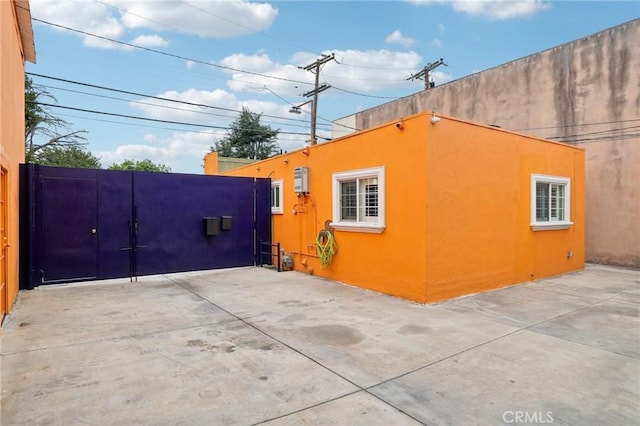 view of side of property with stucco siding and a gate