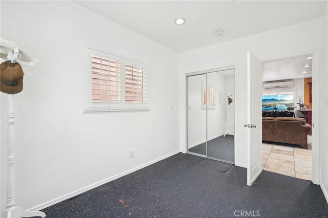unfurnished bedroom featuring a wall unit AC, a closet, baseboards, and recessed lighting