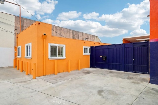 view of side of property featuring a gate and stucco siding