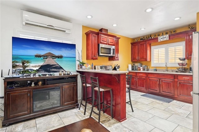 kitchen featuring stainless steel microwave, a wall unit AC, dark brown cabinets, a sink, and recessed lighting