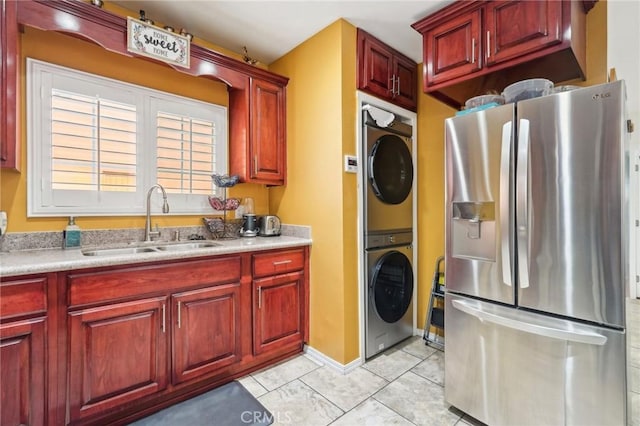 kitchen featuring stainless steel fridge with ice dispenser, a sink, stacked washing machine and dryer, dark brown cabinets, and light countertops