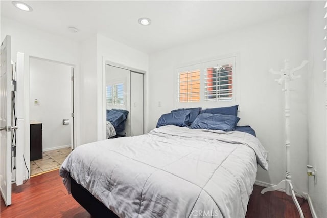 bedroom with a closet, recessed lighting, wood finished floors, and baseboards
