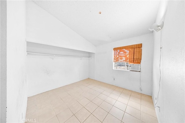 empty room with vaulted ceiling, cooling unit, and light tile patterned floors