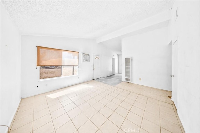 empty room with a heating unit, lofted ceiling, a textured ceiling, light colored carpet, and light tile patterned floors