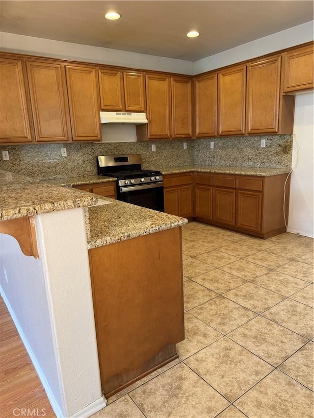 11946 Russell Ct, Victorville, CA 92392 - kitchen featuring gas range, brown cabinetry, light stone counters, under cabinet range hood, and recessed lighting