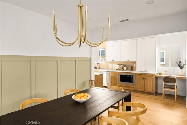 6340 Charlwood St, Lakewood, CA 90713 - kitchen featuring stainless steel dishwasher, light wood finished floors, built in microwave, tasteful backsplash, and light countertops
