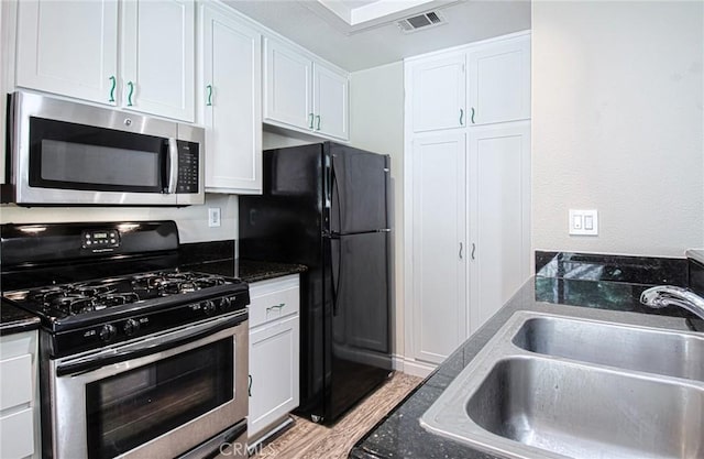 28071 Caldaro, Laguna Niguel, CA 92677 - kitchen with stainless steel appliances, a sink, white cabinets, light wood finished floors, and dark stone countertops