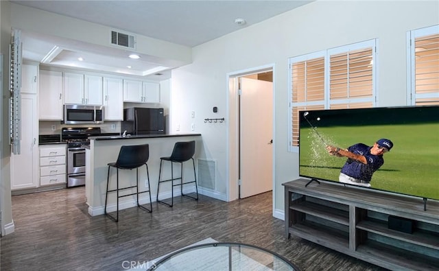 28071 Caldaro, Laguna Niguel, CA 92677 - kitchen with appliances with stainless steel finishes, white cabinets, a kitchen breakfast bar, dark wood finished floors, and a peninsula