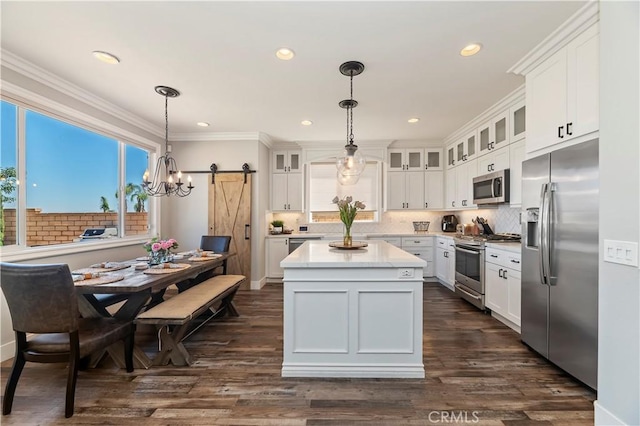 1663 Spyglass Dr, Corona, CA 92883 - kitchen with stainless steel appliances, a barn door, light countertops, white cabinets, and ornamental molding