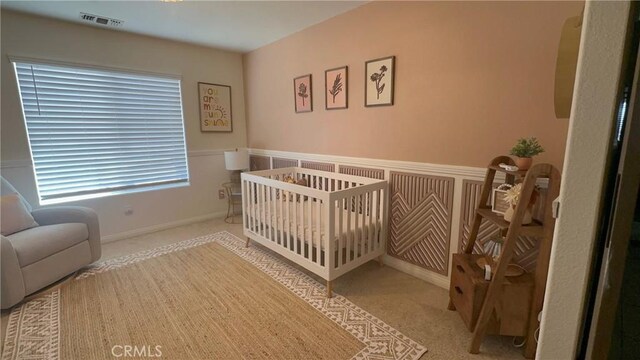 carpeted bedroom with a nursery area and wainscoting