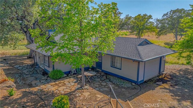 5030 Creek Front Rd, Catheys Valley, CA 95306 - back of property with a shingled roof, a patio area, stucco siding, and a garage