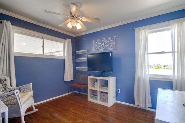 living area with a ceiling fan, plenty of natural light, wood finished floors, baseboards, and crown molding
