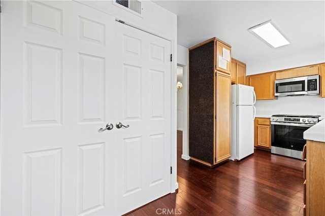 kitchen with appliances with stainless steel finishes, dark wood-type flooring, and light countertops
