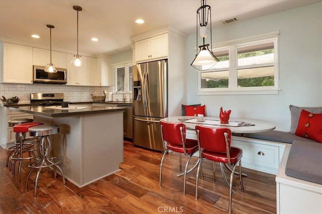 225 Hacienda Ave, San Luis Obispo, CA 93401 - kitchen featuring appliances with stainless steel finishes, dark countertops, white cabinets, dark wood-type flooring, and tasteful backsplash
