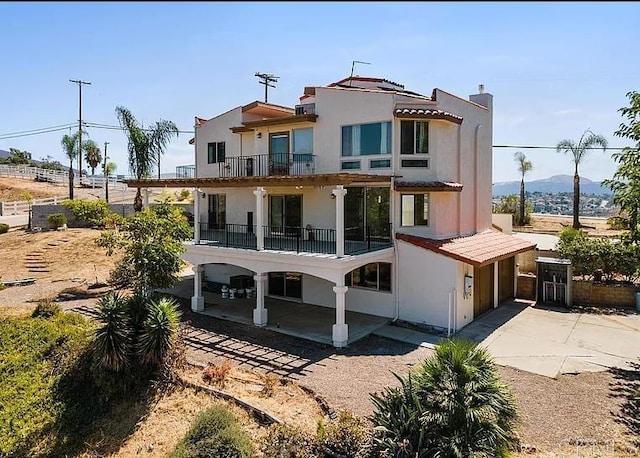 2638 W Victoria Dr, Alpine, CA 91901 - back of property with a balcony, driveway, stucco siding, a patio area, and a chimney