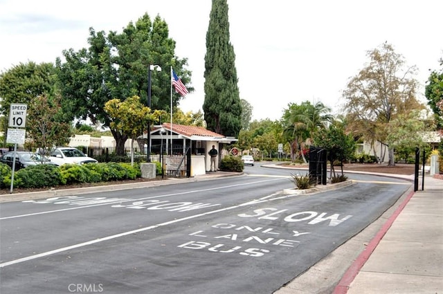 2319 Via Puerta Unit O, Laguna Woods, CA 92637 - view of asphalt road featuring traffic signs, curbs, and street lighting