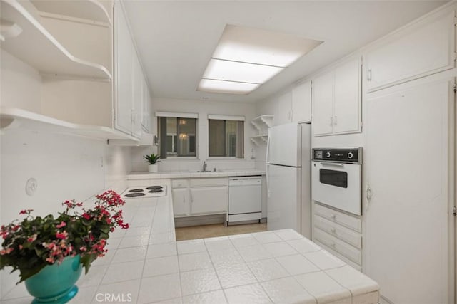 2319 Via Puerta Unit O, Laguna Woods, CA 92637 - kitchen with open shelves, white appliances, tile counters, and white cabinetry