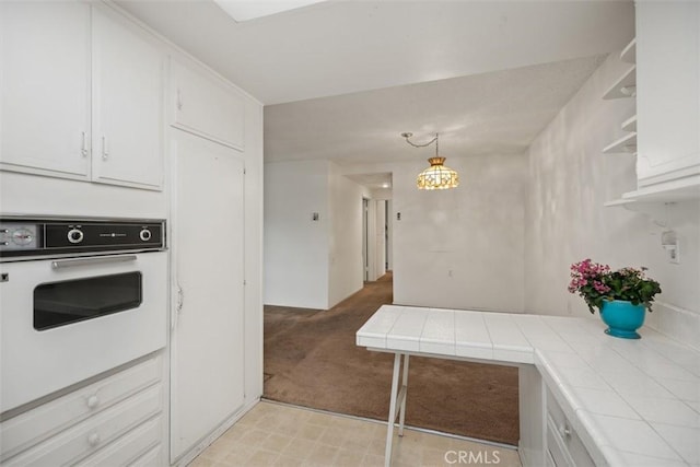 2319 Via Puerta Unit O, Laguna Woods, CA 92637 - kitchen featuring oven, tile counters, light colored carpet, and white cabinets