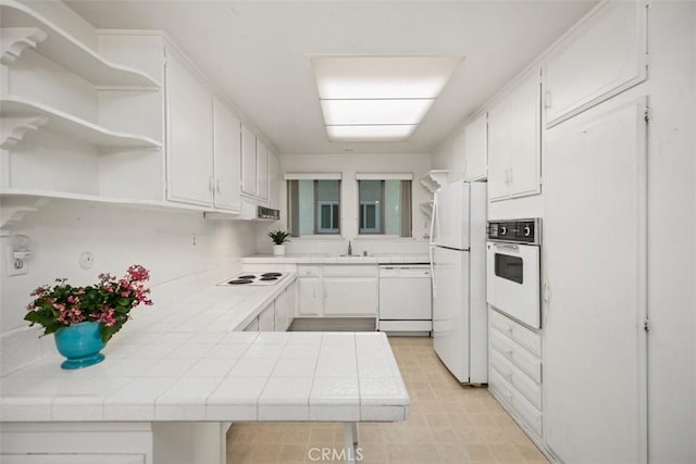 2319 Via Puerta Unit O, Laguna Woods, CA 92637 - kitchen with white appliances, a sink, tile counters, open shelves, and a peninsula