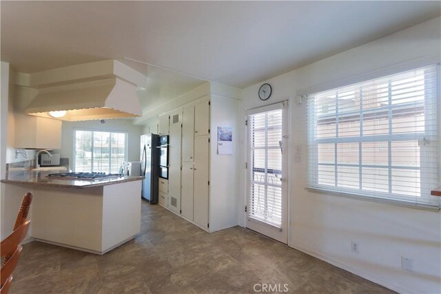 9943 Vernon Ave, Montclair, CA 91763 - kitchen with freestanding refrigerator, stainless steel gas stovetop, a sink, a peninsula, and white cabinets