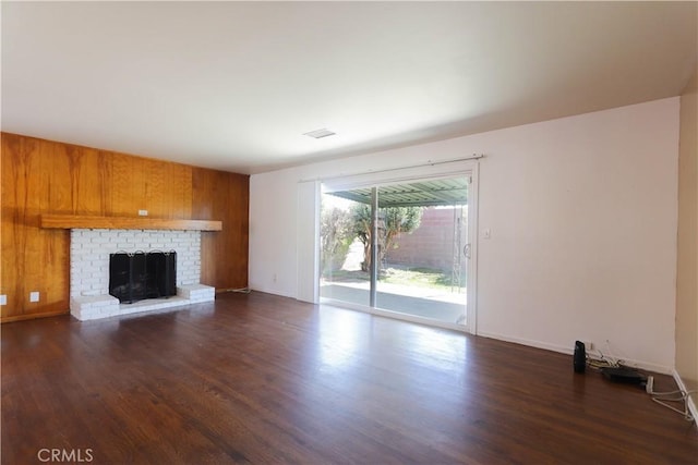 9943 Vernon Ave, Montclair, CA 91763 - unfurnished living room featuring dark wood-style floors, a brick fireplace, baseboards, and wood walls