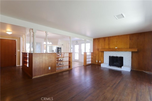 9943 Vernon Ave, Montclair, CA 91763 - unfurnished living room featuring dark wood-style floors, a brick fireplace, a chandelier, and wooden walls