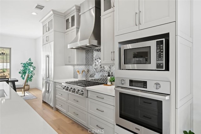 4140 Hillside Dr, San Luis Obispo, CA 93401 - kitchen with appliances with stainless steel finishes, wall chimney exhaust hood, light countertops, tasteful backsplash, and light wood finished floors