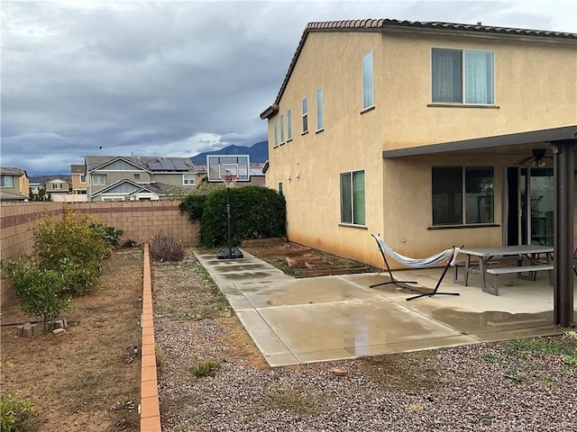 rear view of house featuring fence, a patio, stucco siding, and ceiling fan