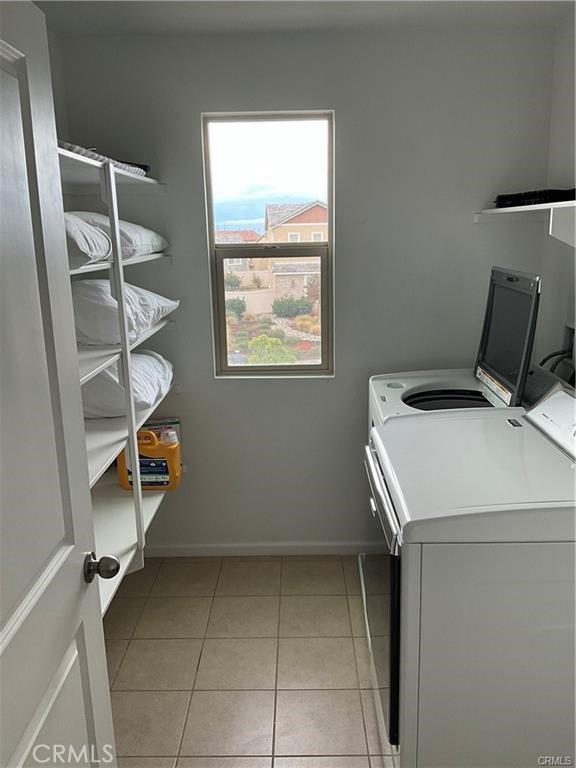 washroom with separate washer and dryer, light tile patterned flooring, and baseboards