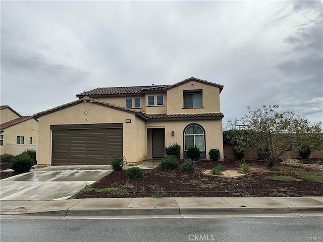 mediterranean / spanish-style house with stucco siding, driveway, a tiled roof, and an attached garage