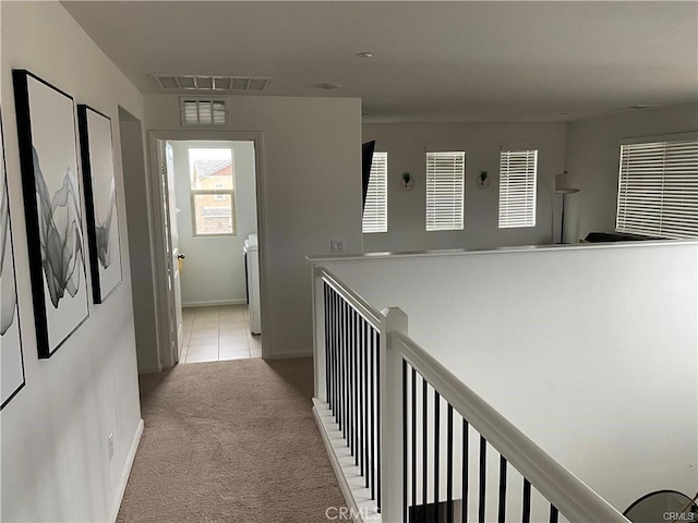 hall with light colored carpet, baseboards, and light tile patterned floors