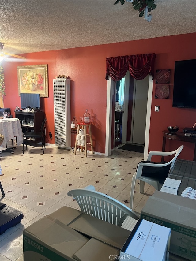 living room featuring a heating unit, a textured ceiling, and light tile patterned floors