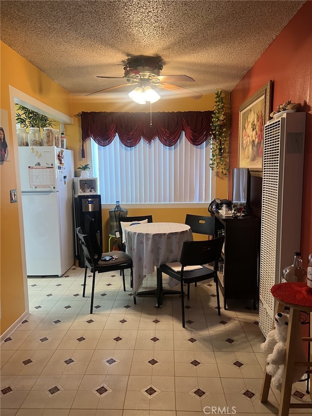 dining area with a heating unit, ceiling fan, a textured ceiling, and light tile patterned flooring