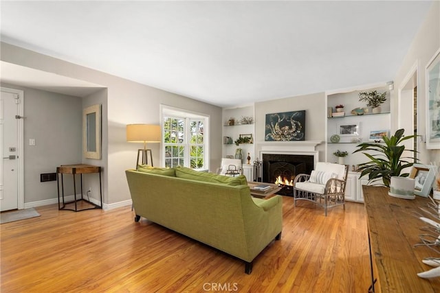 426 Ultimo Ave, Long Beach, CA 90814 - living room with a warm lit fireplace, light wood-style flooring, built in shelves, and baseboards