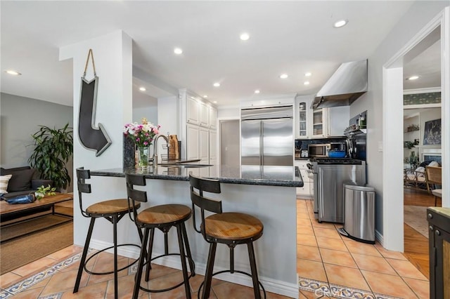 426 Ultimo Ave, Long Beach, CA 90814 - kitchen with stainless steel appliances, a peninsula, white cabinets, a kitchen breakfast bar, and light tile patterned floors