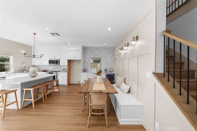 16225 Orizaba Ave, Paramount, CA 90723 - dining space featuring beverage cooler, stairway, light wood finished floors, and recessed lighting